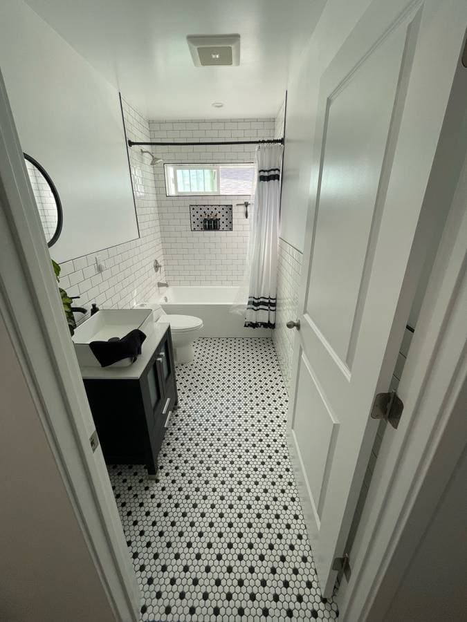 picture of a newly remodeled custom bathroom with black and white textured tile and new ceramic white luxury sink and cabinets