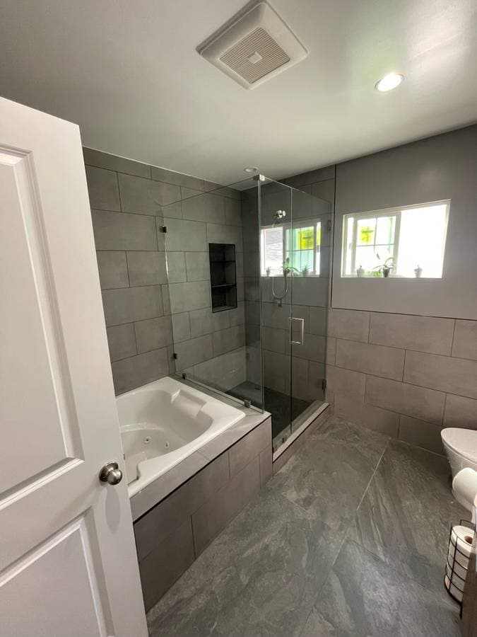 picture of a newly remodeled custom bathroom with full bathtub and glass shower doors
