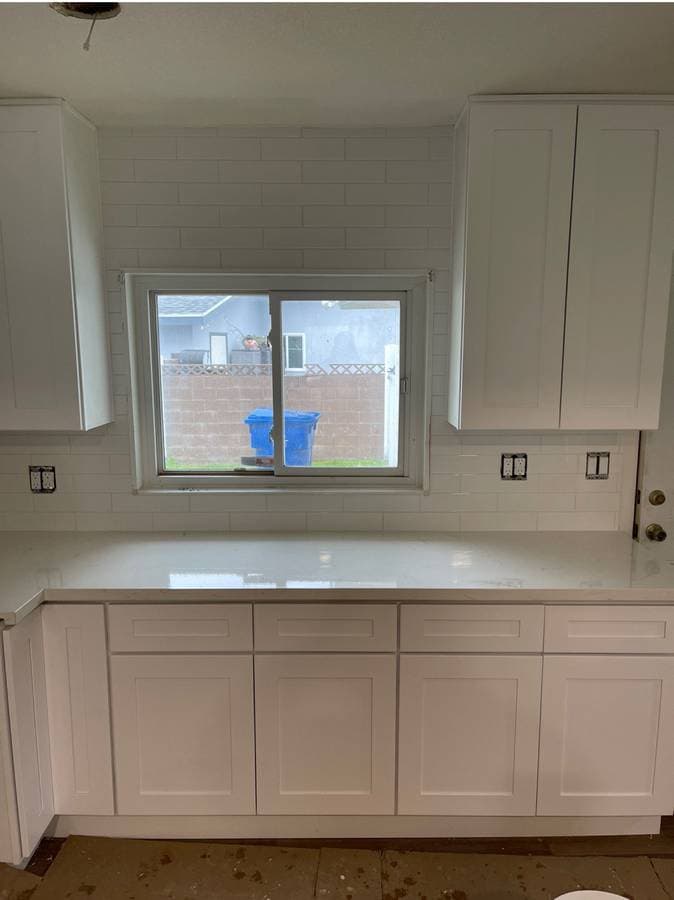 Picture of a newly renovated kitchen with white granite countertops, new white windows, and new white cabinets